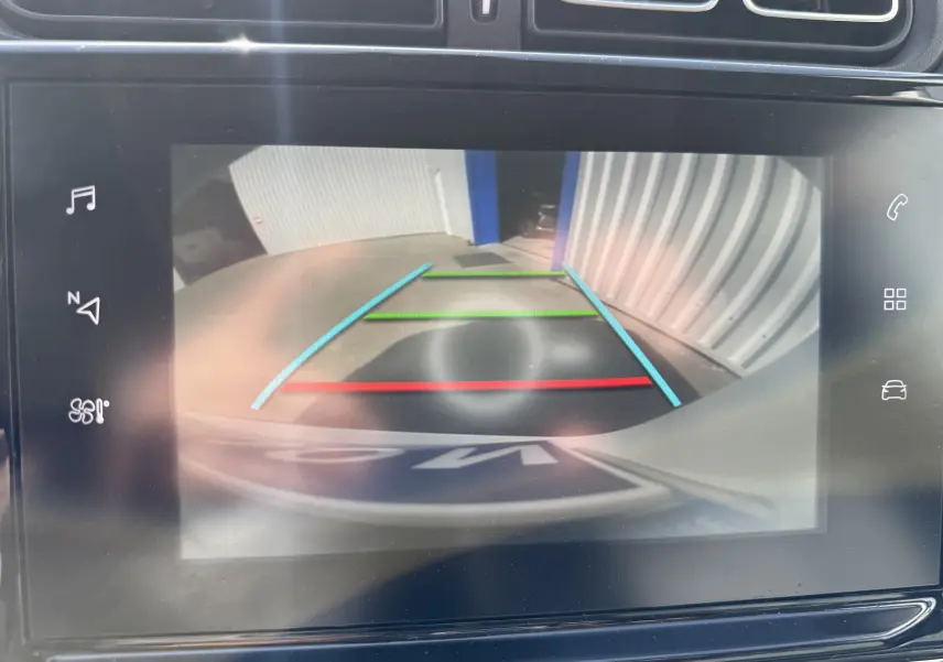 Affichage de la caméra de recul de la Citroën C3 2019, montrant l'arrière avec les lignes de guidage colorées sur fond de sol et mur gris.