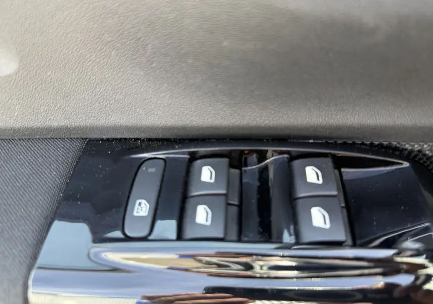 Gros plan sur les commandes des vitres électriques côté conducteur d'une Citroën C3 blanche toit noir, version 2019.