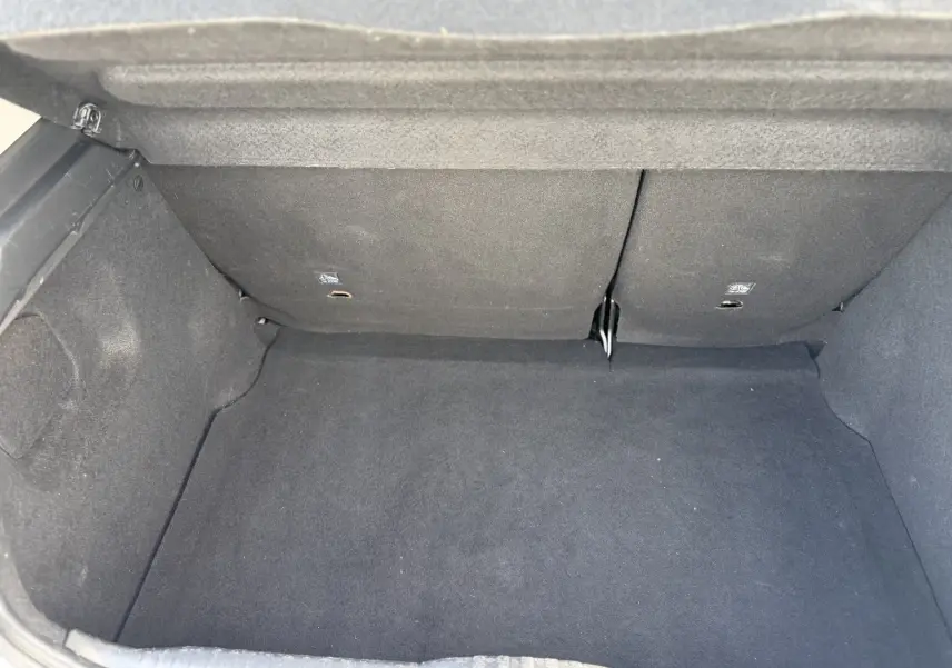 Vue intérieure du coffre vide de la Citroën C3 1.2 PureTech 83 Origins, avec revêtement noir uniforme.