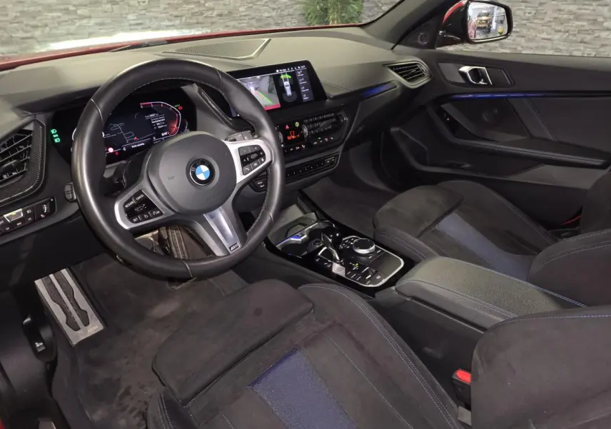 Vue intérieure côté conducteur de la BMW Série 1 116d M Sport 2024 avec sellerie Alcantara noire et tableau de bord numérique.