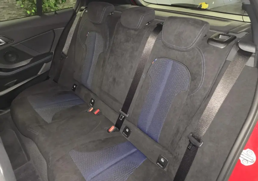 Vue intérieure arrière des sièges en tissu et Alcantara noir et bleu de la BMW Série 1 116d M Sport rouge 2024.