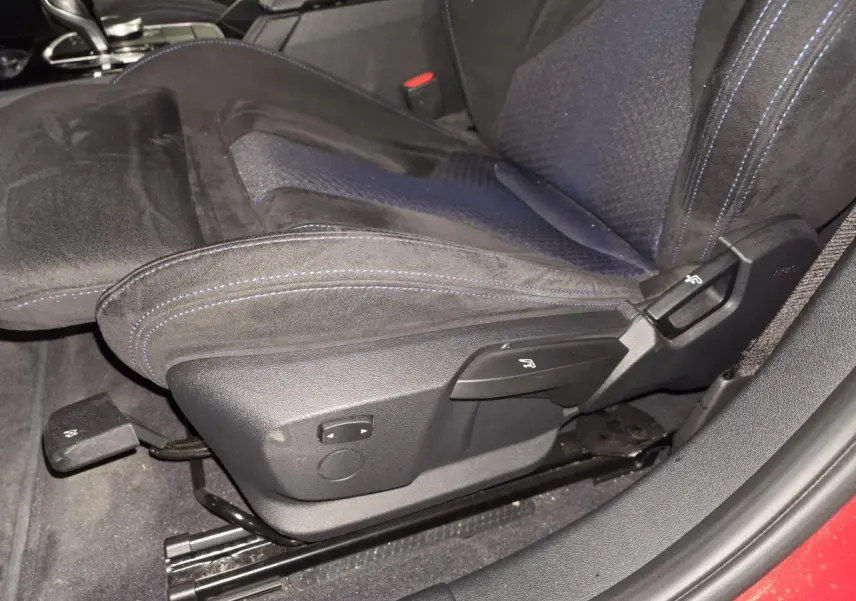 Gros plan sur le siège avant gauche en tissu et Alcantara noir avec surpiqûres bleues dans une BMW Série 1 rouge.