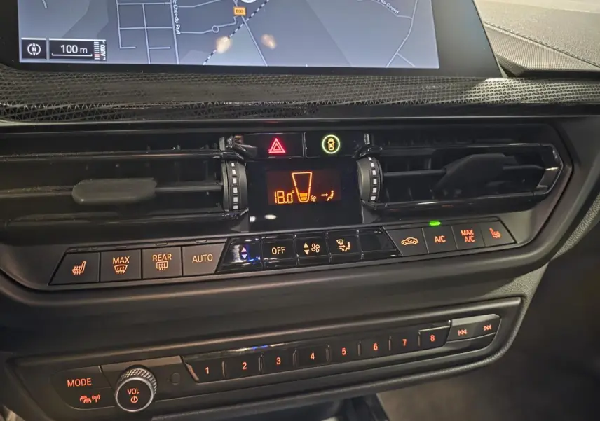 Détail de la console centrale de la BMW Série 1 116d M Sport 2024 avec commandes climatisation et écran tactile.