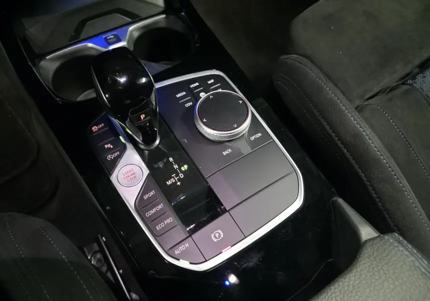 Gros plan sur la console centrale noire avec sélecteur de boîte automatique et molette iDrive de la BMW Série 1 rouge.