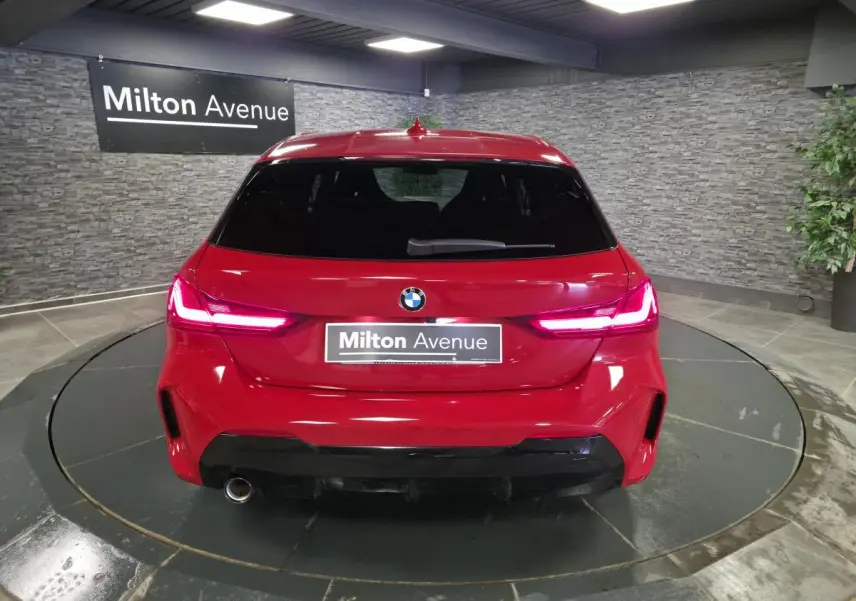 Vue arrière d'une BMW Série 1 116d M Sport rouge métallisé avec feux LED et sortie d'échappement chromée.