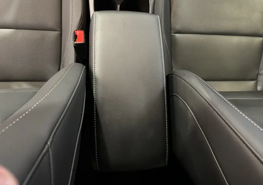 Vue rapprochée de l'accoudoir central en cuir noir avec surpiqûres blanches entre les sièges avant du MG ZS 1.5 Hybrid+ 197 Luxury.