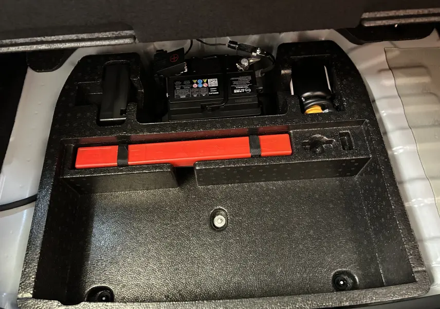 Compartiment de rangement sous plancher de coffre avec batterie et triangle de signalisation rouge du MG ZS 1.5 Hybrid+ 197 Luxury blanc.