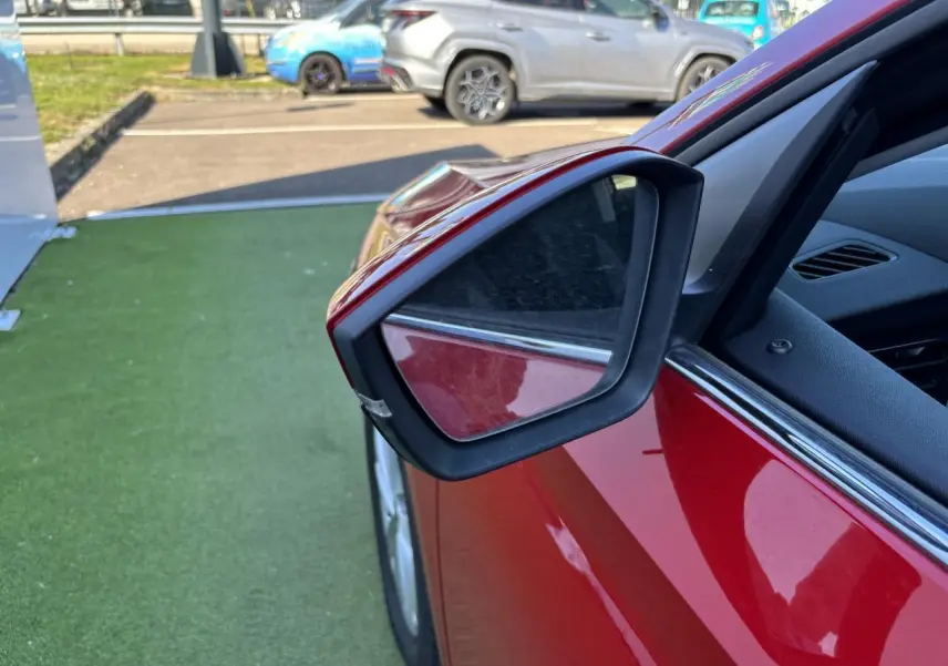 Rétroviseur extérieur côté gauche d'une Skoda Scala rouge Velvet Metal, avec partie de la portière visible.