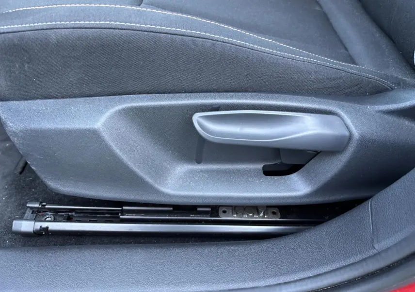 Détail de la commande manuelle de réglage du siège conducteur sur une SKODA SCALA rouge Velvet Metal 2024.