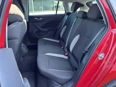 Vue latérale de l'intérieur arrière d'une Skoda Scala rouge Velvet Metal, sièges tissu gris avec inserts clairs et ceintures visibles.
