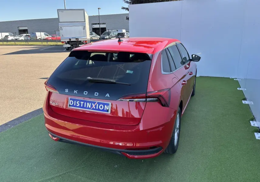Vue 3/4 arrière droite d'une Skoda Scala rouge Velvet Metal avec feux arrière LED et logo distinctif sur fond urbain.