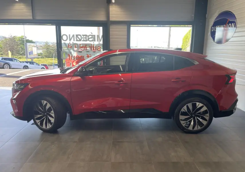 Profil côté gauche de la Renault Rafale rouge à toit noir, avec jantes alliage noires et vitres surteintées, en intérieur showroom.