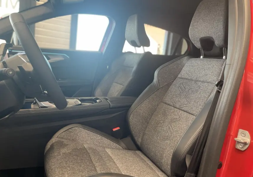 Intérieur côté conducteur du Renault Rafale 2025, siège sport gris textile avec surpiqûres, portière rouge visible.