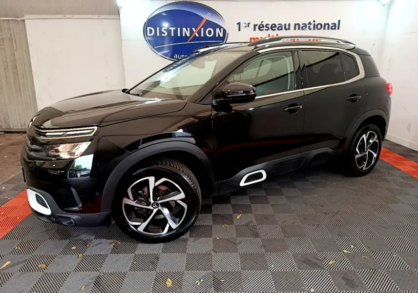 Vue 3/4 avant droit d'un Citroën C5 Aircross noir avec jantes alliage et détails blancs sur boucliers et bas de caisse.