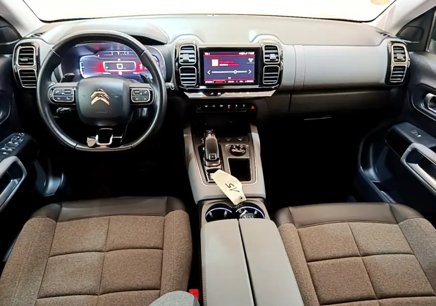 Intérieur du Citroën C5 Aircross 2020 vu de face, volant cuir noir et écran tactile central lumineux rouge.