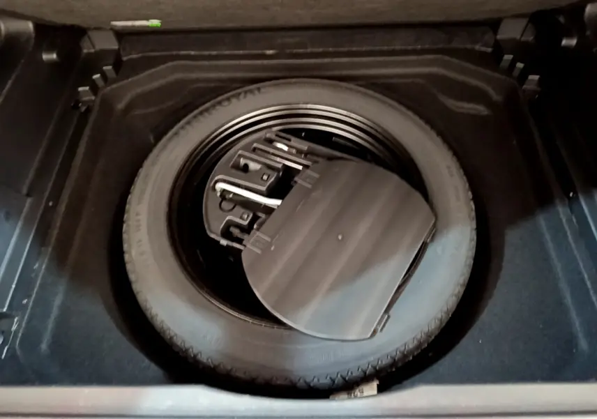 Vue plongeante sur la roue de secours noire et ses outils dans le coffre du Citroën C5 Aircross noir de 2020