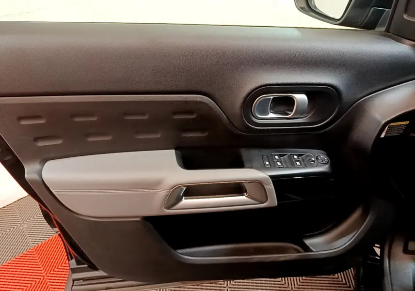 Intérieur côté gauche de la porte avant d'une Citroën C5 Aircross noire, avec commandes de vitres et poignée argentée.