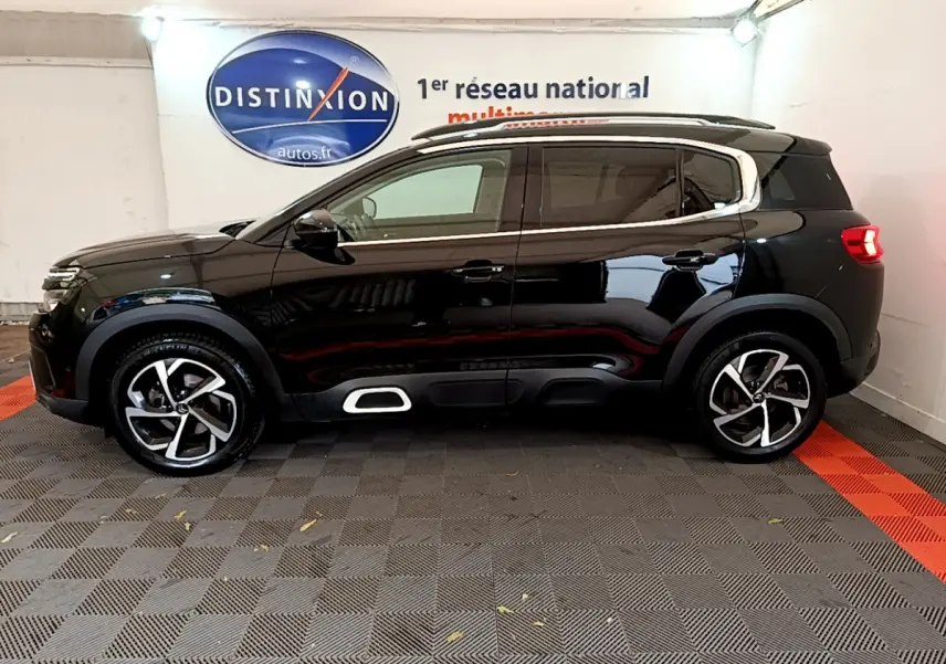 Profil côté gauche d'un SUV Citroën C5 Aircross noir 2020 avec jantes alliage et barres de toit visibles.
