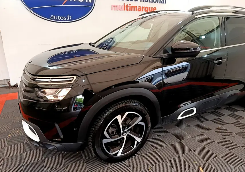 Vue 3/4 avant gauche d'un Citroën C5 Aircross noir avec jantes alliage et détails blancs sur le bouclier et bas de caisse.