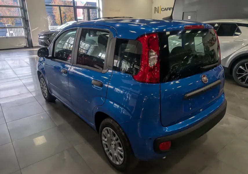 Vue 3/4 arrière droite d'une FIAT Panda 1.0 70 CH Hybrid City bleu Italia en showroom, avec feux arrière rouges distinctifs.
