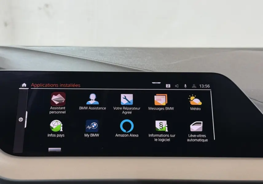 Écran tactile central affichant les applications connectées dans une BMW Série 1 116d Business Design, intérieur beige.