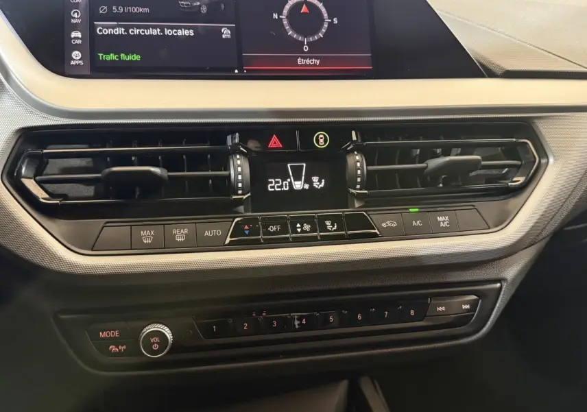 Vue rapprochée du tableau de bord central de la BMW Série 1 116d noir, avec écran tactile et commandes climatisation.