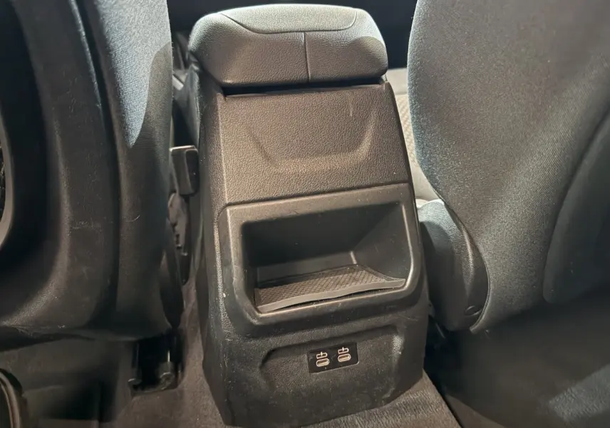 Gros plan sur la console centrale arrière noire avec ports USB, entre les sièges arrière gris foncé d'une BMW Série 1 116d.