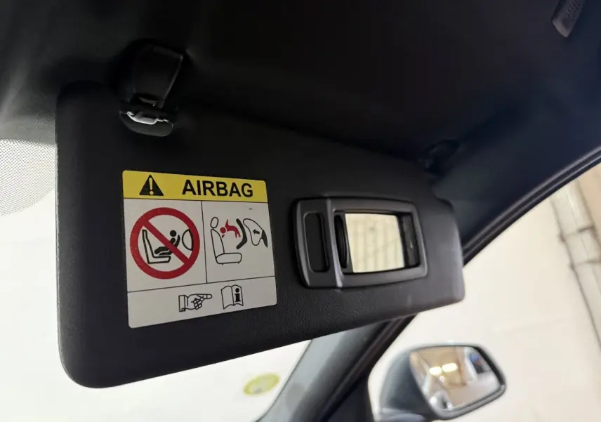 Détail du pare-soleil côté conducteur avec miroir et avertissement airbag dans BMW Série 1 noir 116d 2022.