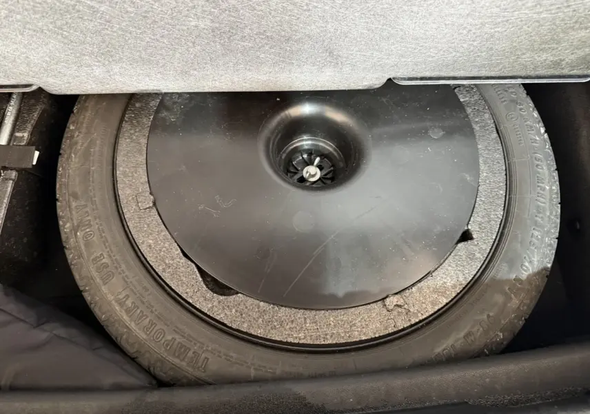 Vue rapprochée du pneu de secours noir dans le coffre d'une BMW Série 1 116d Business Design 2022.