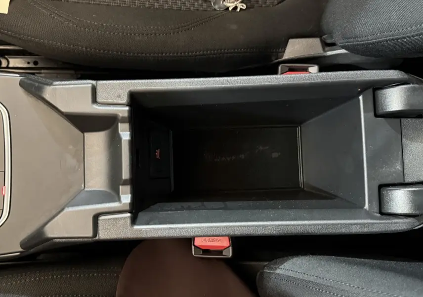 Vue plongeante sur le rangement central noir entre les sièges avant d'une BMW Série 1 116d Business Design 2022.