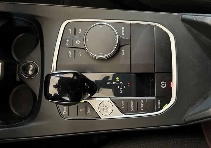 Vue plongeante sur la console centrale noire de la BMW Série 1 116d avec levier de vitesses automatique et commandes de mode de conduite.