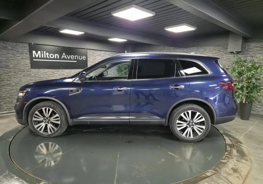 Renault Koleos bleu de Saxe vu de profil côté gauche, avec jantes alliage 19 pouces et vitres teintées.