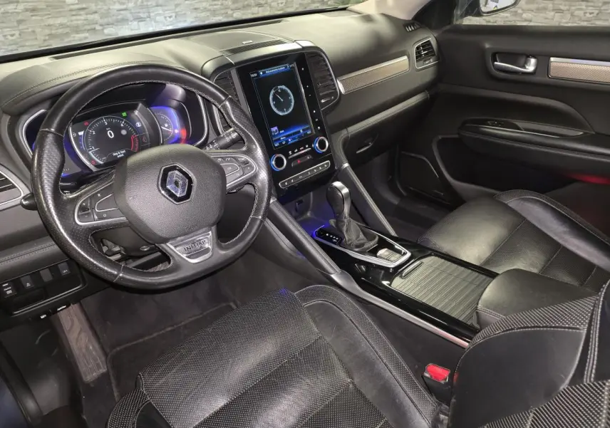 Vue intérieure côté conducteur du Renault Koleos bleu, avec volant cuir Initiale Paris et écran tactile vertical central.