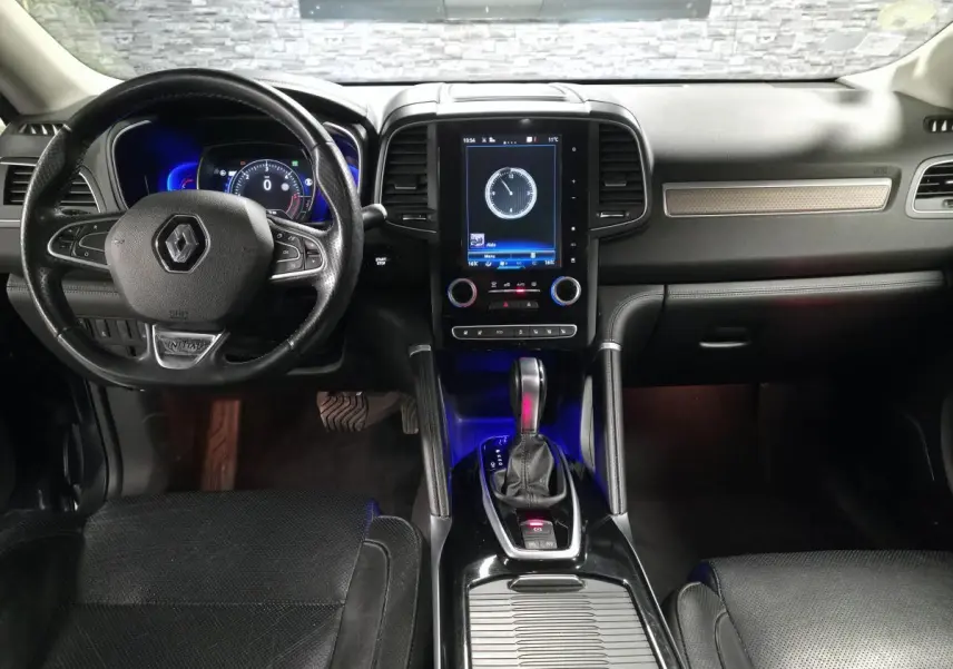 Vue intérieure avant du Renault Koleos 2017, tableau de bord noir avec écran tactile vertical et volant cuir siglé Renault.