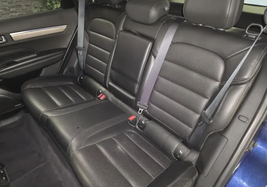 Vue intérieure des sièges arrière en cuir noir du Renault Koleos bleu, avec accoudoir central relevé et ceinture de sécurité.