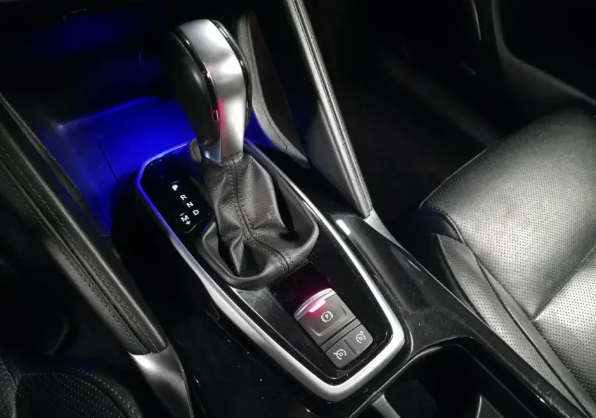 Gros plan sur la console centrale du Renault Koleos bleu, mettant en valeur le levier de vitesse automatique et l'éclairage bleu ambiant.