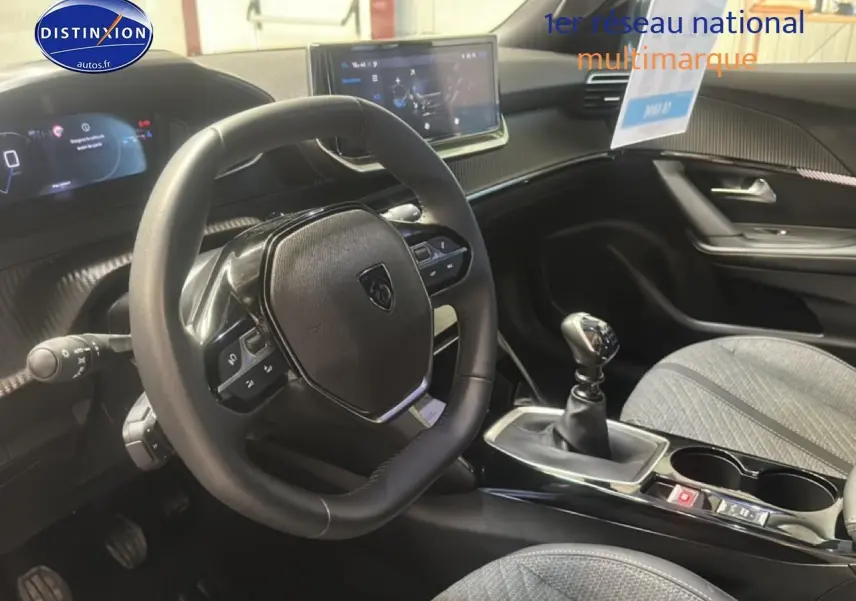 Intérieur de la Peugeot 2008 1.2 100 Allure 2025, vue côté conducteur sur volant, tableau de bord et levier de vitesse manuel.