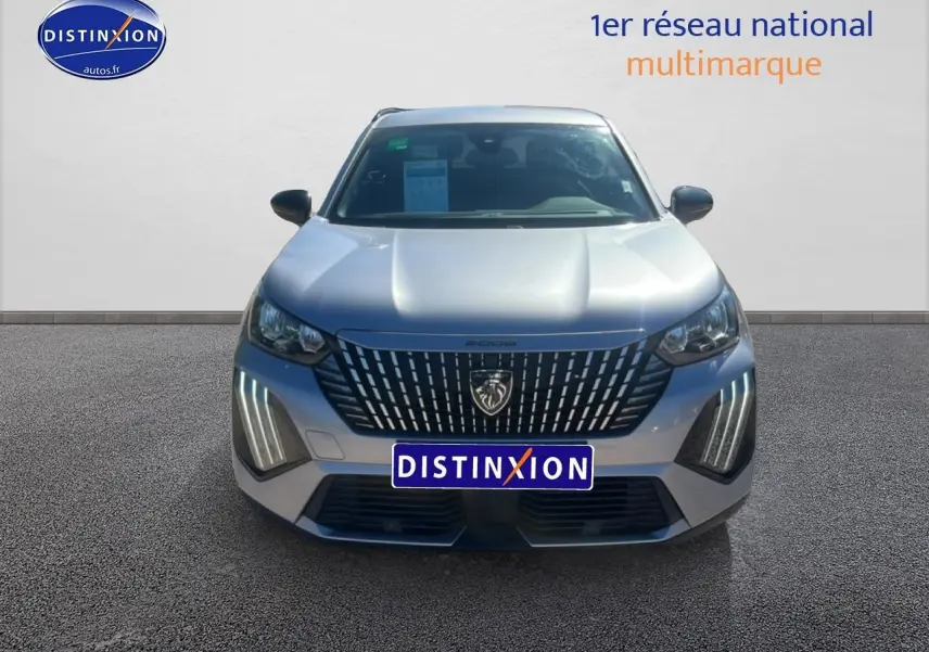 Vue frontale d'un Peugeot 2008 gris artense avec calandre distinctive et feux LED verticaux allumés.