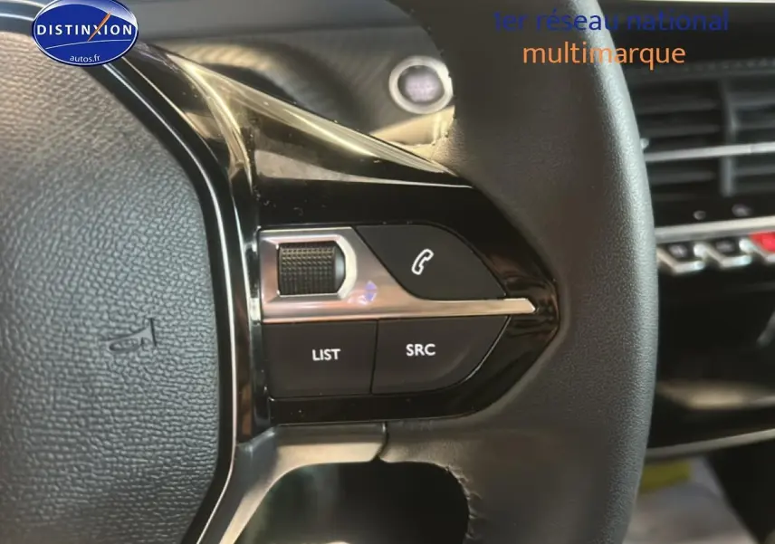 Gros plan sur les commandes gauche du volant noir du Peugeot 2008 gris artense, avec boutons multifonctions.