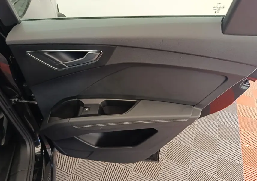 Vue rapprochée de la porte arrière gauche noire de l'Audi Q4 E-Tron Sportback 2023 avec garniture sobre et poignée argentée.
