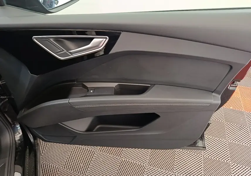 Vue intérieure de la porte avant gauche noire de l'Audi Q4 E-Tron Sportback avec poignée argentée et garniture noire.