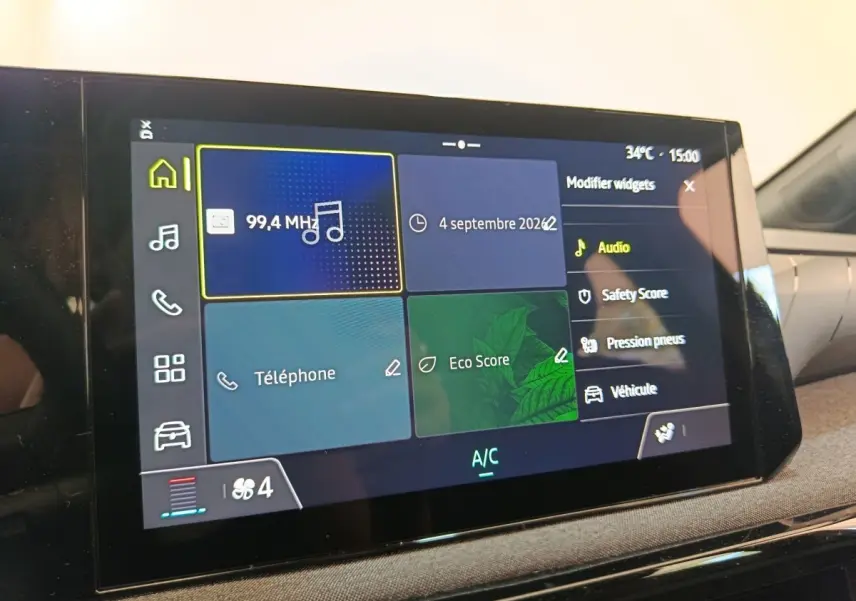Écran tactile central de la Renault Clio bleu, affichant les options audio, téléphone et score écologique en intérieur.