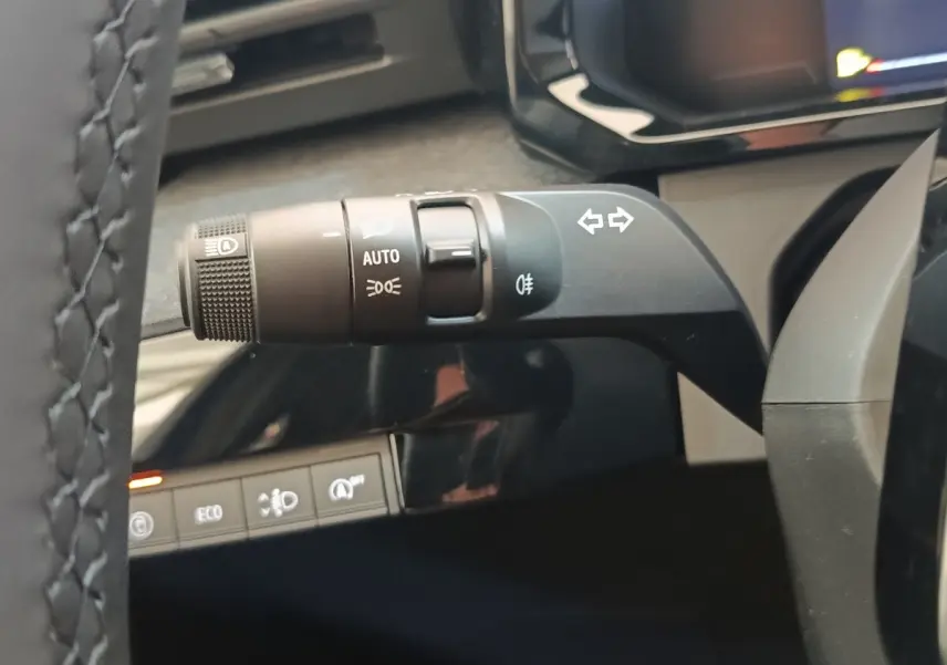 Gros plan sur la commande de clignotants et feux automatiques du volant de la Renault Clio bleu, intérieur moderne.