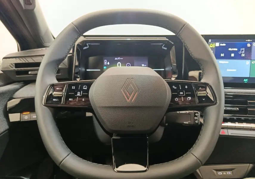 Vue rapprochée du volant multifonctions noir de la Renault Clio 2026 avec tableau de bord digital et écran central tactile.