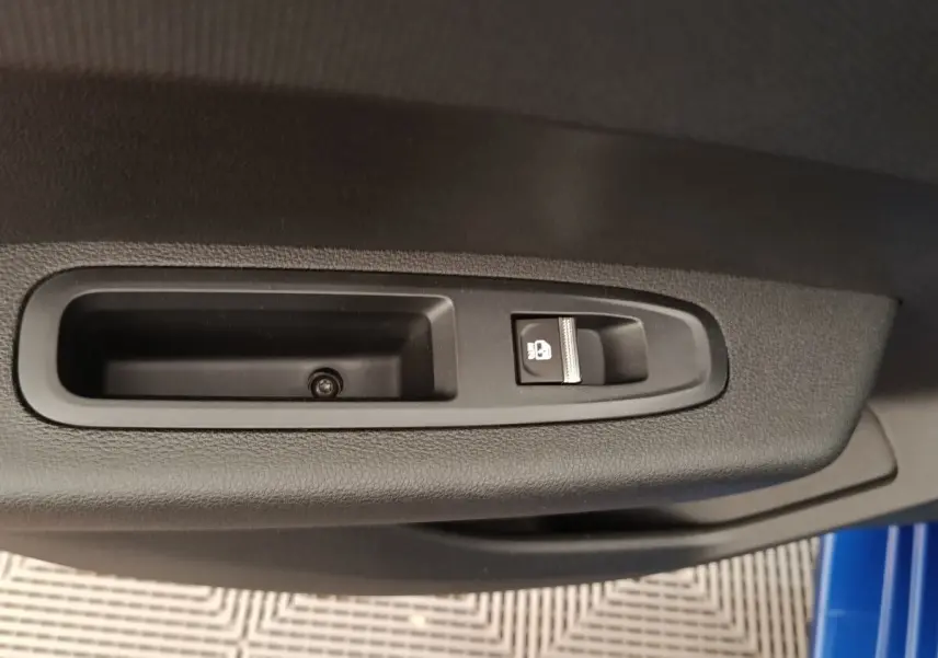 Détail de la commande de verrouillage des portes sur la portière côté gauche d'une Renault Clio bleu 2026.