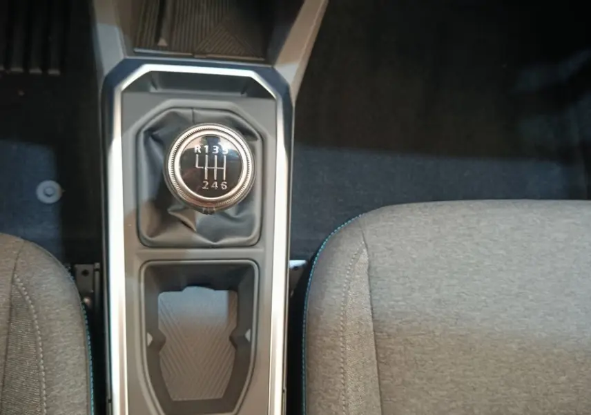 Vue plongeante sur la console centrale de la Renault Clio bleu, avec levier de vitesse manuel et frein à main électrique.