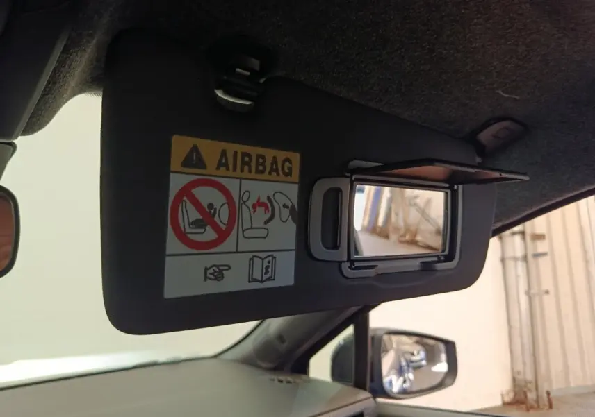 Détail du pare-soleil côté conducteur avec miroir intégré et avertissement airbag dans une Renault Clio bleu 2026.