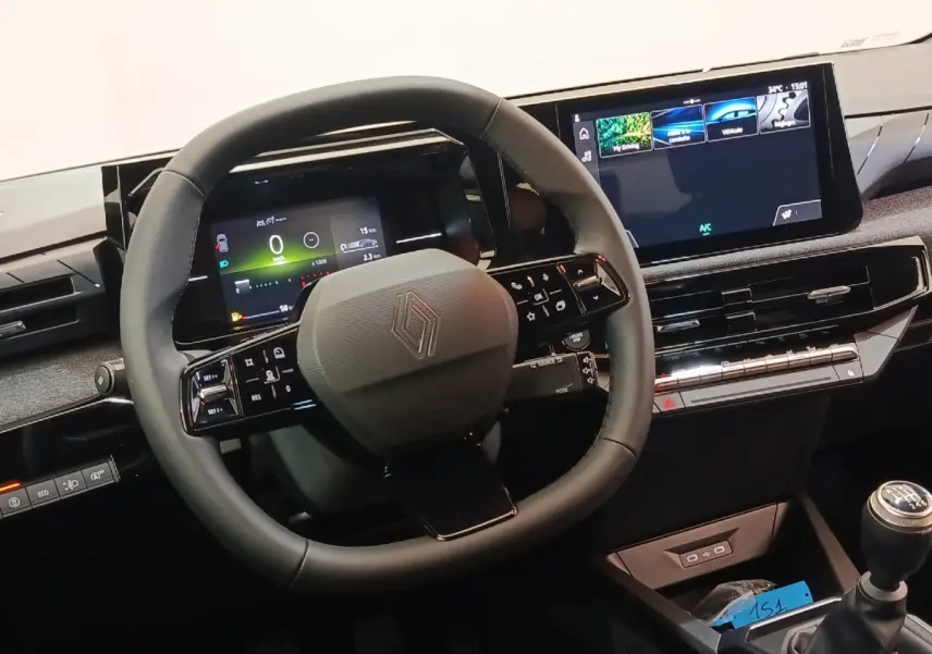 Vue rapprochée du volant multifonctions noir et du tableau de bord numérique de la Renault Clio bleu essence 2026.