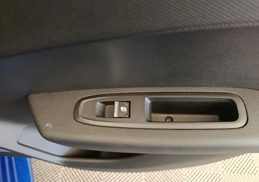 Détail de la commande de verrouillage des portes sur la portière côté gauche d'une Renault Clio bleue.