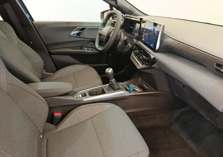Intérieur avant droit de la Renault Clio bleu 2026, avec tableau de bord numérique et boîte manuelle visible.